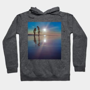 Silhouetted people in a row on a sand beach. Hoodie